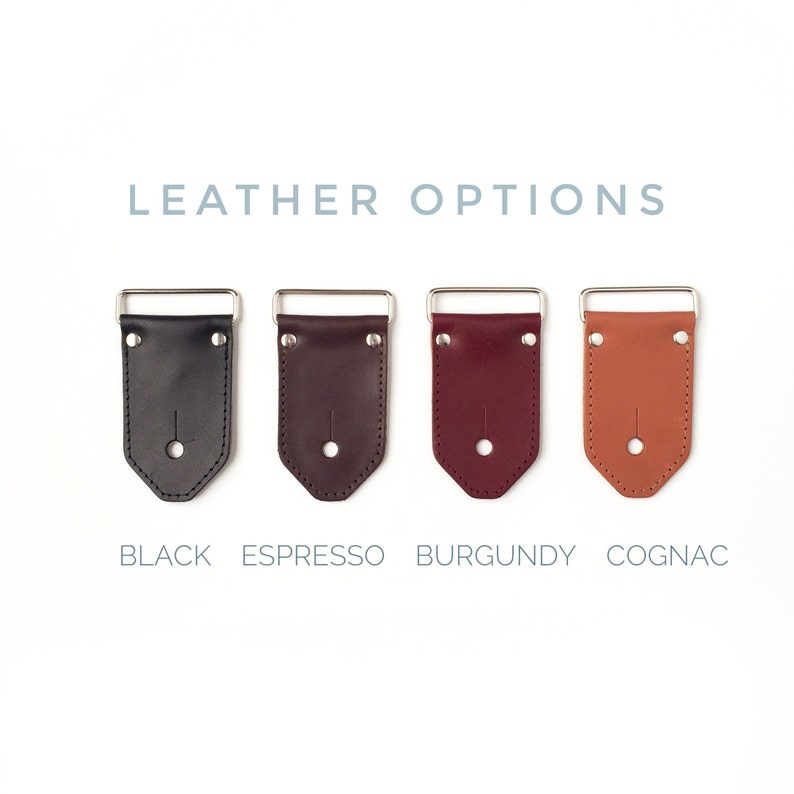 May include: Four leather strap end pieces in black, espresso, burgundy, and cognac colors. The strap ends are made of leather and have a metal buckle. The text "LEATHER OPTIONS" is above the strap ends. The text "BLACK", "ESPRESSO", "BURGUNDY", and "COGNAC" are below the strap ends.