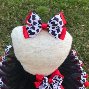 May include: Black and red tulle tutu with a cow print ribbon and a red and cow print bow.