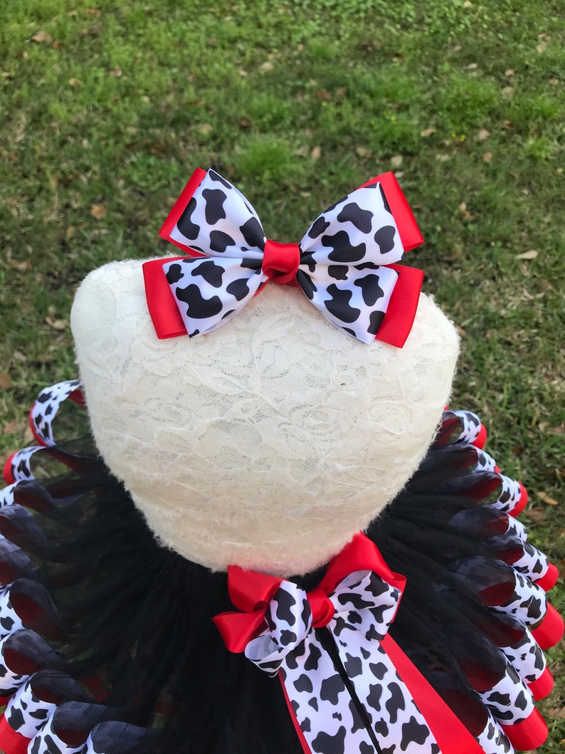May include: Black and red tulle tutu with a cow print ribbon and a red and cow print bow.