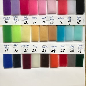 May include: A color chart of 54" x 40" tulle fabric swatches. The swatches are arranged in rows and columns, with each swatch labeled with a number and a color name. The colors include purple, lavender, fuchsia, hot pink, pink, light pink, coral, white, black, emerald green, apple green, baby maize, yellow, gold, old gold, turquoise, sky blue, aqua blue, royal blue, navy, burgundy, ivory, brown, orange, red, gray, and hunter green.