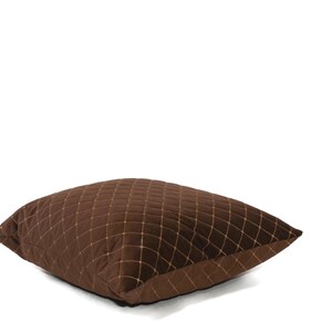 May include: A brown quilted throw pillow with a diamond pattern. The pillow is made of a soft, plush fabric and has a subtle sheen.