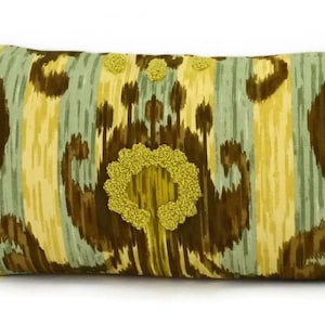 May include: Rectangular decorative pillow with a patterned design in shades of brown, yellow, and light blue. The pillow features a central floral design and three smaller floral accents. The pillow is designed for home decor.