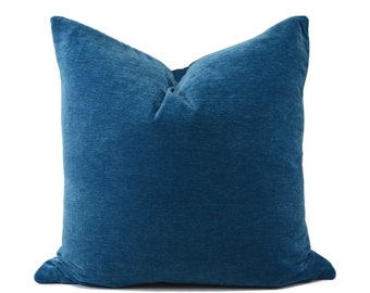 May include: A teal blue throw pillow with a soft, textured fabric. The pillow is square shaped and has a simple design.