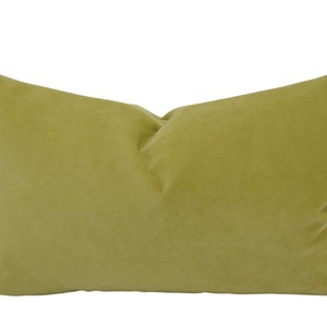 May include: A rectangular, olive-green pillow with a soft, velvety texture. The pillow is a solid color and has a simple, elegant design. It is a decorative item for a bed or sofa.
