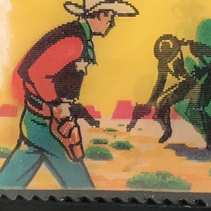 May include: A vintage illustration of two cowboys in a desert landscape. One cowboy is wearing a red shirt, blue jeans, and a brown hat. The other cowboy is wearing a green shirt and blue jeans. The cowboys are standing in front of a cactus.