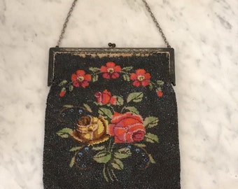 May include: A vintage beaded purse with a floral design. The purse is black with red, orange, yellow, and green beads. It has a silver chain strap and a fringe bottom.