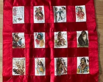 May include: A red satin quilt with 12 squares. Each square features a different vintage trading card with images of Native Americans, a monkey, and a man in a suit. The text on the quilt reads "Be sure to live on the sunny side".
