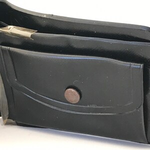 May include: A black leather wallet with a single pocket and a metal button closure.