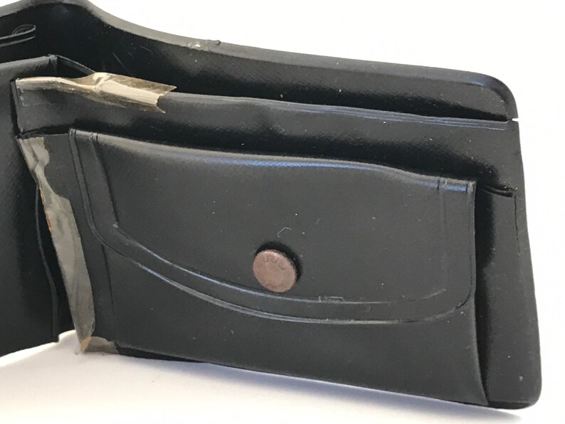 May include: A black leather wallet with a single pocket and a metal button closure.
