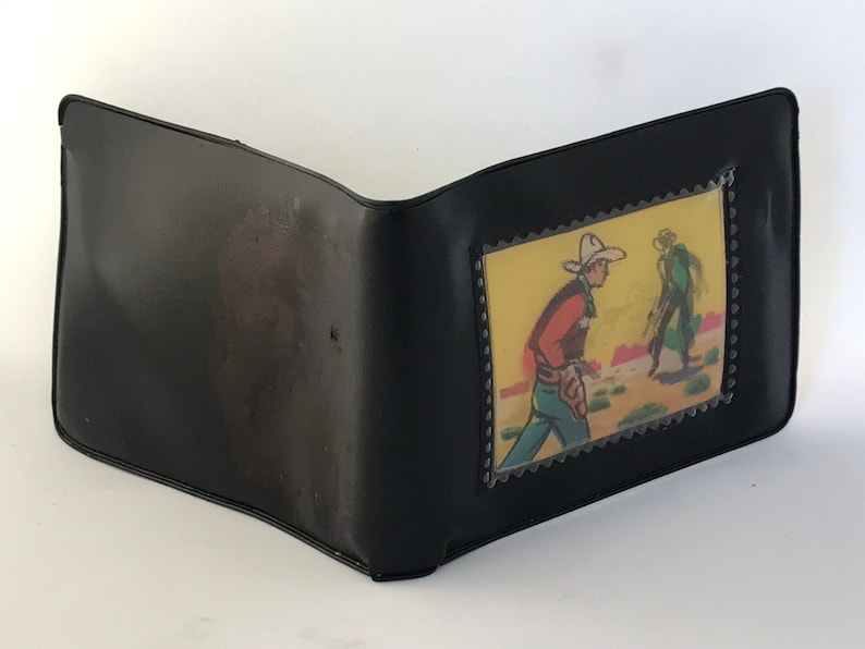 May include: Black leather wallet with a clear plastic window displaying a vintage comic book illustration of two cowboys in a desert setting.