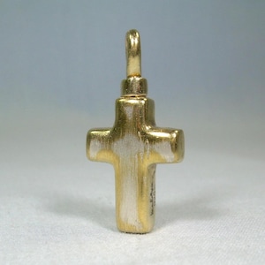 May include: A gold-colored cross pendant with a silver-colored body. The cross has a loop at the top for a chain. The cross is a religious symbol, often worn as jewelry.
