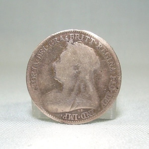 May include: A silver coin featuring a profile of a person, with text around the edge. The coin is displayed on a clear stand against a light background. The coin's details are visible, including the inscription and the portrait.