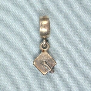 May include: Silver charm in the shape of a graduation cap. The charm is designed to be added to a bracelet or necklace.