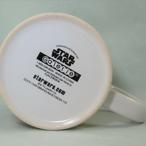 Puede incluir: Taza de cer&aacute;mica blanca con un logotipo de Star Wars negro y el texto "Galerie" y "starwars.com". La taza es apta para lavavajillas y microondas y est&aacute; hecha en China.
