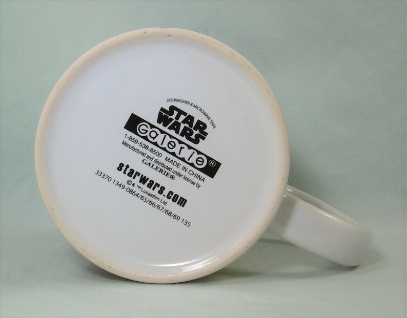 Puede incluir: Taza de cer&aacute;mica blanca con un logotipo de Star Wars negro y el texto "Galerie" y "starwars.com". La taza es apta para lavavajillas y microondas y est&aacute; hecha en China.