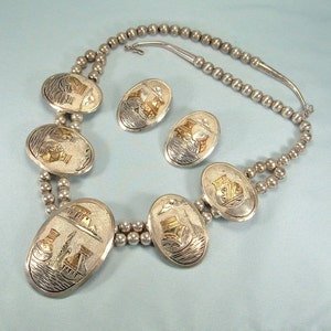 Puede incluir: Un collar de plata y oro con una cadena de cuentas y colgantes ovalados con un diseño estilizado. El collar viene con un par de pendientes a juego.