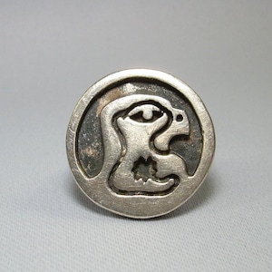 May include: A silver ring with a stylized animal design. The ring is round and has a smooth surface.