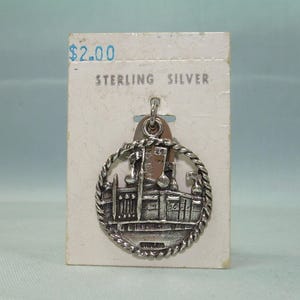 May include: Sterling silver charm pendant featuring a detailed depiction of a building with a rope border. The charm is on a white card with the text "$2.00 STERLING SILVER".