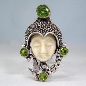 Puede incluir: Una taza de cerámica blanca con un asa negra y el texto "But First, Coffee" en negrita negra. La taza se encuentra sobre un fondo borroso, sugiriendo un ambiente acogedor.