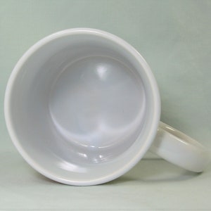 Puede incluir: Taza de cer&aacute;mica blanca con un acabado liso y brillante. La taza tiene una forma redondeada y un asa.