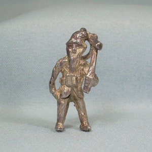 Op de afbeelding: Een zilveren bedel van een kabouter met een hoed en een stok. De kabouter staat met zijn benen uit elkaar en zijn armen gestrekt.