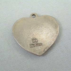 May include: Silver heart-shaped pendant with a small inscription that reads "925 Italy".
