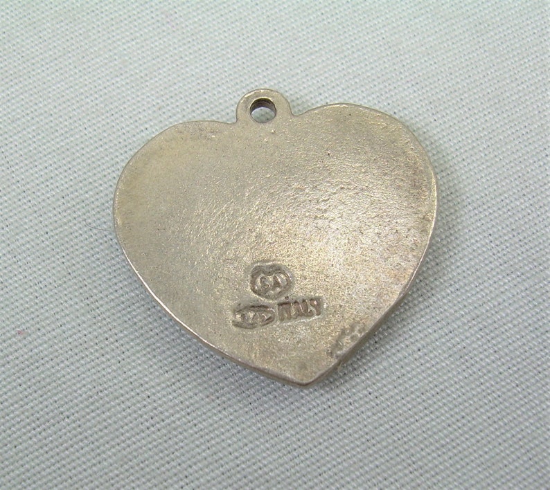 May include: Silver heart-shaped pendant with a small inscription that reads "925 Italy".