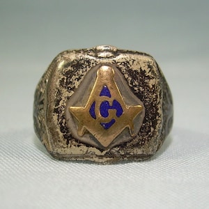 May include: A silver Masonic ring with a gold square and compass design. The compass has a blue enamel center with a letter 'G' inside.