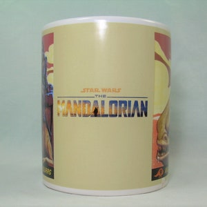Puede incluir: Una taza de cer&aacute;mica blanca con un fondo beige que presenta el logotipo de Star Wars: The Mandalorian. El logotipo est&aacute; en un esquema de color amarillo, naranja y azul. La taza tiene un gr&aacute;fico de un personaje del programa en el lado izquierdo y un gr&aacute;fico de una criatura del programa en el lado derecho.