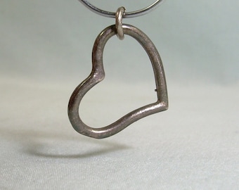 May include: A silver heart-shaped pendant hangs from a silver chain.