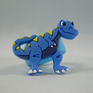 May include: Blue and yellow dinosaur-shaped rubber bracelet.