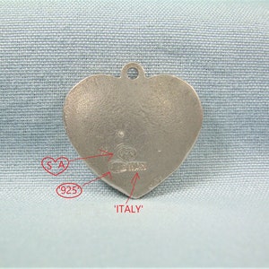 May include: Silver heart-shaped charm with the words 'ITALY' and '925' stamped on the back. The charm also has the letters 'SA' and a maker's mark.