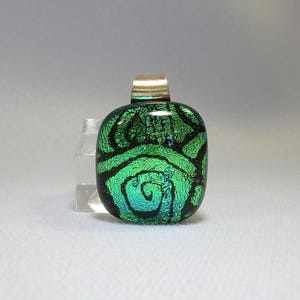 May include: A green glass pendant with a silver bail. The glass has a swirling pattern and iridescent finish.