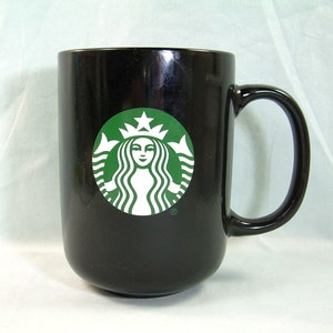 May include: Black ceramic mug with a green Starbucks logo featuring a mermaid with a crown and the letter R.