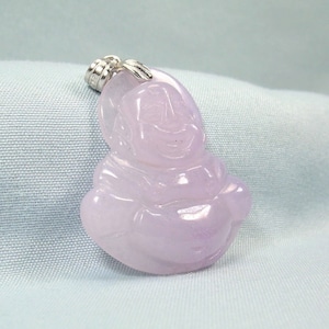May include: A lavender jade pendant carved in the shape of a smiling Buddha. The pendant is attached to a silver bail.