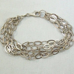 Peut inclure: Un bracelet en argent avec plusieurs rangs de maillons ovales.