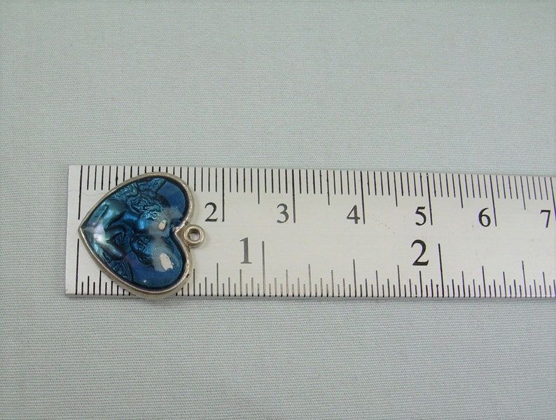 May include: A blue and silver heart-shaped charm with a detailed image of a couple embracing. The charm is approximately 1 inch in size and has a loop for attaching to a necklace or bracelet.