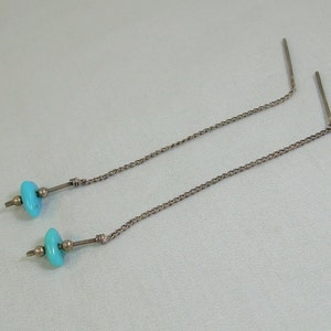 May include: A pair of turquoise dangle earrings with silver chains and beads.