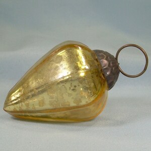 May include: A gold glass Christmas bauble with a textured surface and a metal hanger.