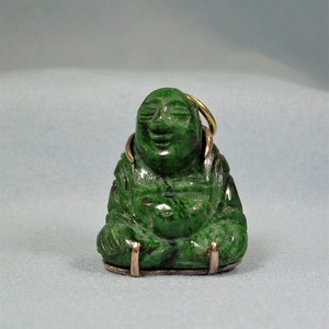 May include: A green jade Buddha charm pendant with gold accents. The Buddha is sitting in a meditative pose with a serene expression.