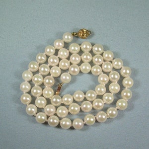 May include: A strand of white pearl beads with a gold clasp. The pearls are round and smooth, and the necklace is approximately 18 inches long.
