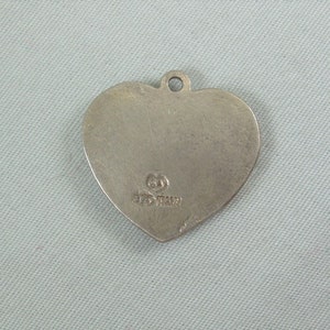 May include: Silver heart-shaped pendant with a small inscription on the back. The inscription reads "925 Italy".