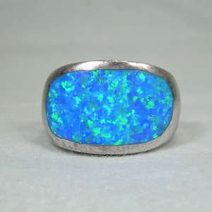 May include: A silver ring featuring a large blue and green opal gemstone.