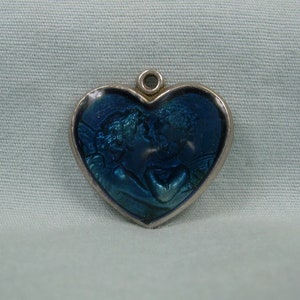 May include: A silver heart-shaped charm with a blue enamel design of two angels embracing.
