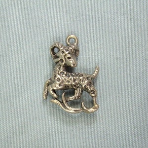 以下が含まれることがあります： テクスチャ加工された表面を持つ、跳ねている鹿の形をしたシルバーチャーム