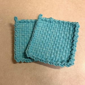 May include: Two teal blue woven pot holders with a braided edge.
