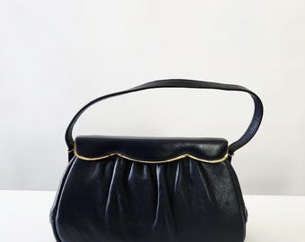 Bolsa vintage de couro genuíno azul, estilo meados do século XX (década de 1950), com alça superior e detalhes em metal dourado.