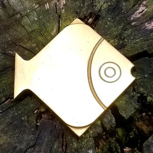 May include: A gold-colored metal fish-shaped wall decor with a circular design on its body.