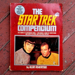 May include: A red book cover with the title "The Star Trek Compendium" in yellow and white letters. The book is a 20th anniversary edition and includes a show-by-show guide and over 125 rare photos. The cover features a photo of William Shatner and Leonard Nimoy.