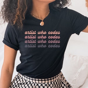 May include: Black t-shirt with the text "artist who codes" repeated four times in a gradient of pink and white.